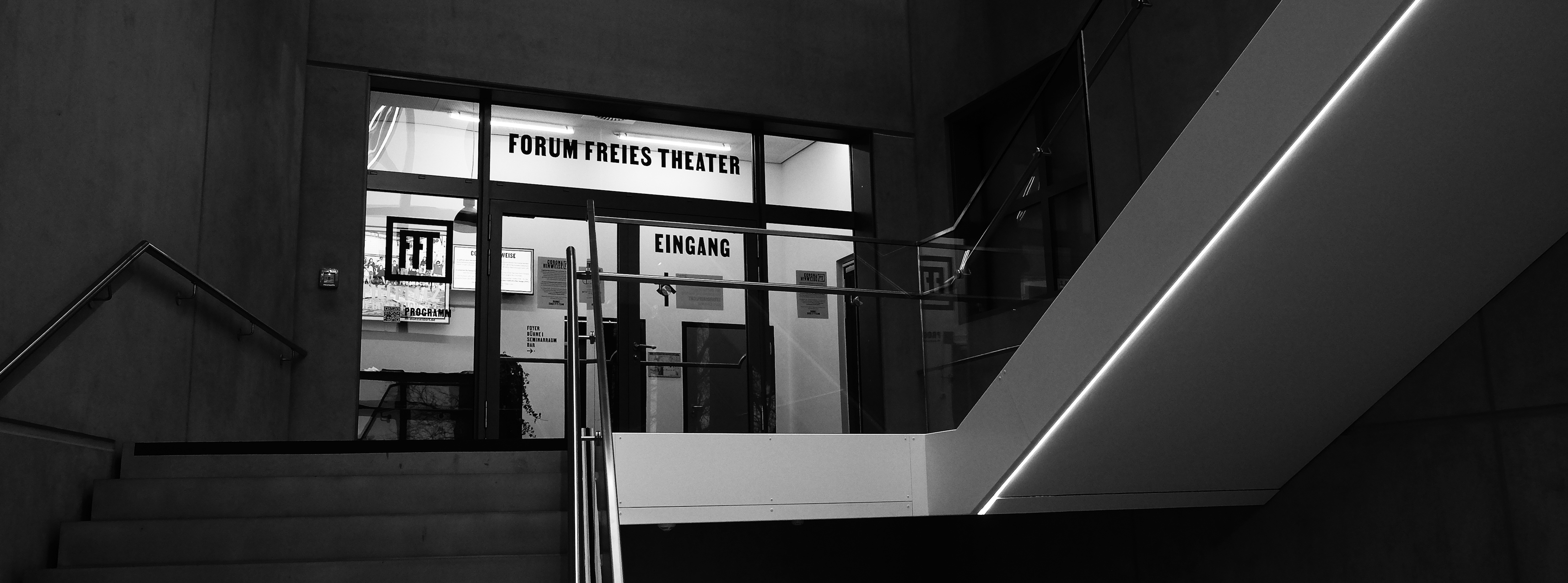 Ein Foto vom Eingangsbereich des FFT. Zu sehen sind verglaste Türen, mit Oberlichtern. Auf ihnen steht Forum Freies Theater geschrieben.