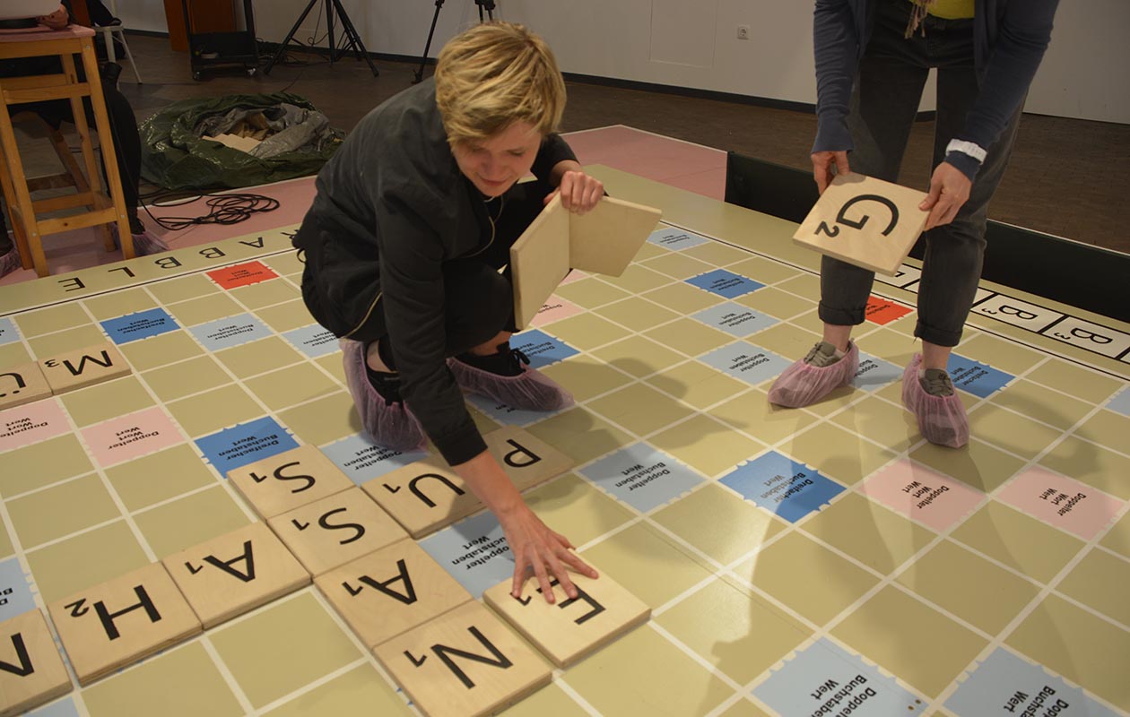Zwei Personen spielen ein übergroßes Scrabble-Spiel.